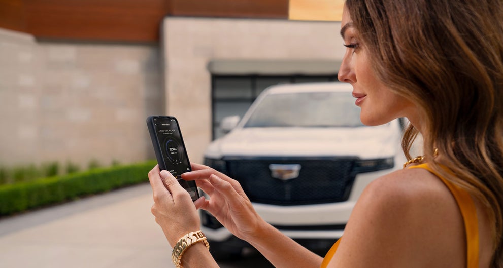 lady checking her mobile with a Cadillac vehicle background | Spearfish Cadillac in Spearfish SD